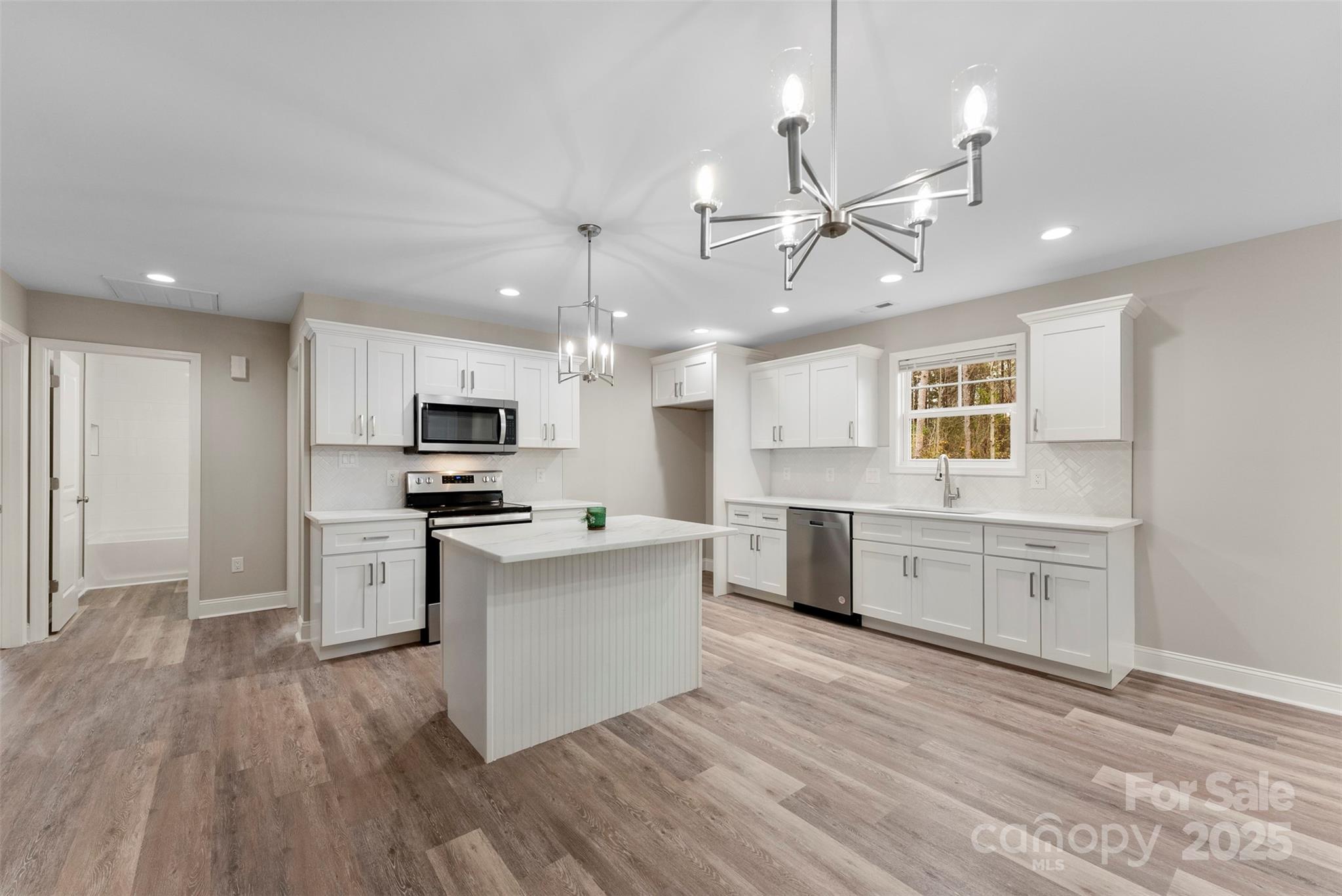 a large kitchen with cabinets wooden floor and stainless steel appliances