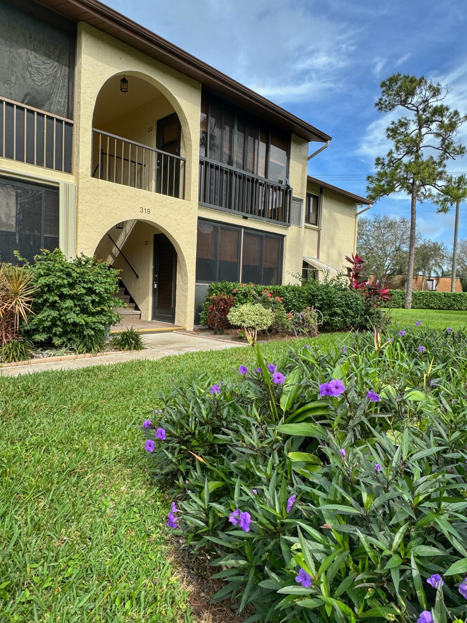 a front view of a house with a big yard and potted plants