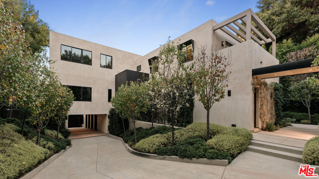 a front view of a house with trees and plants