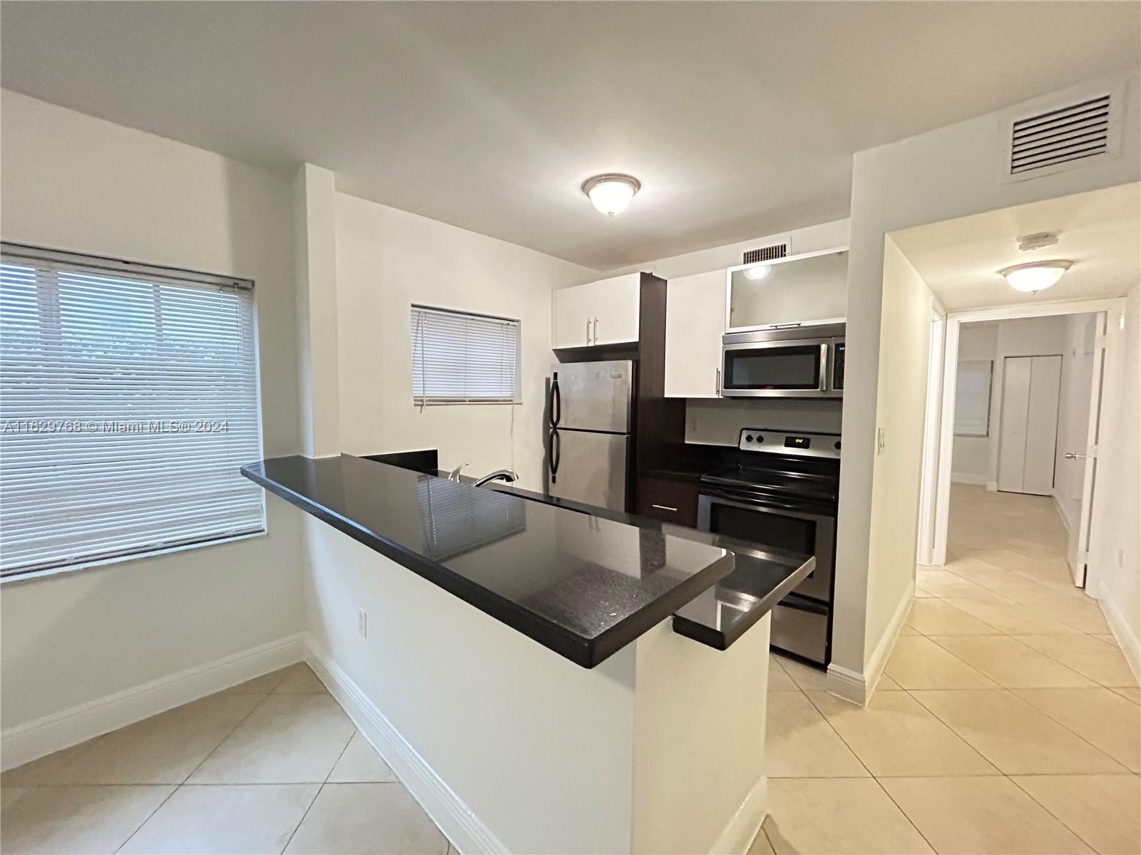 a kitchen with stainless steel appliances granite countertop a sink and a refrigerator