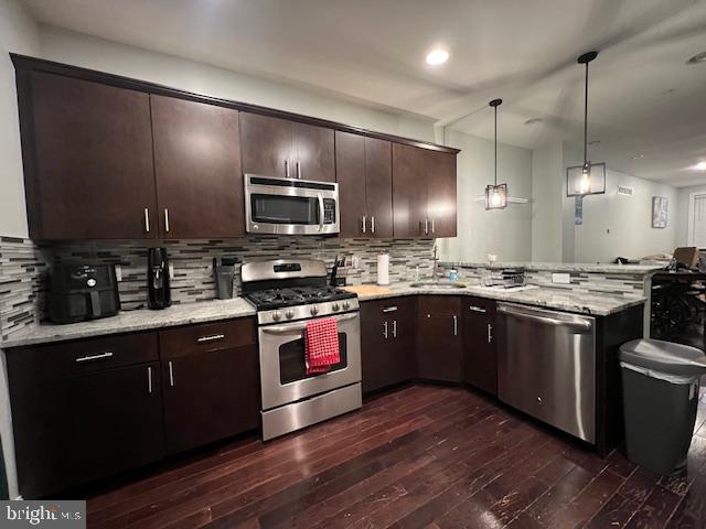 a kitchen with stainless steel appliances kitchen island granite countertop a stove a sink dishwasher a refrigerator and a microwave oven on the wooden floor