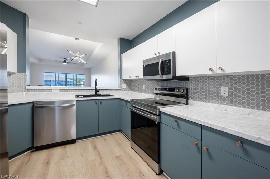 Kitchen featuring light hardwood / wood-style flooring, sink, white cabinets, pendant lighting, and appliances with stainless steel finishes