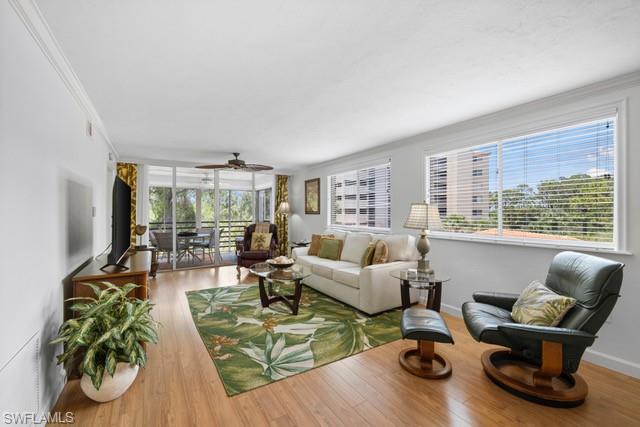 a living room with furniture floor to ceiling window and wooden floor