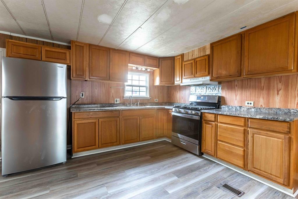 a kitchen with granite countertop a refrigerator stove top oven and sink