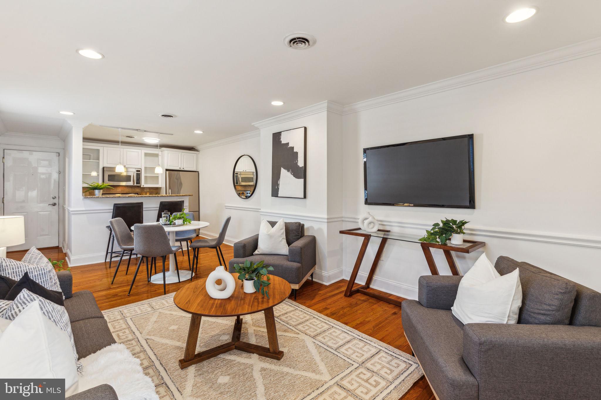 a living room with furniture kitchen view and a flat screen tv