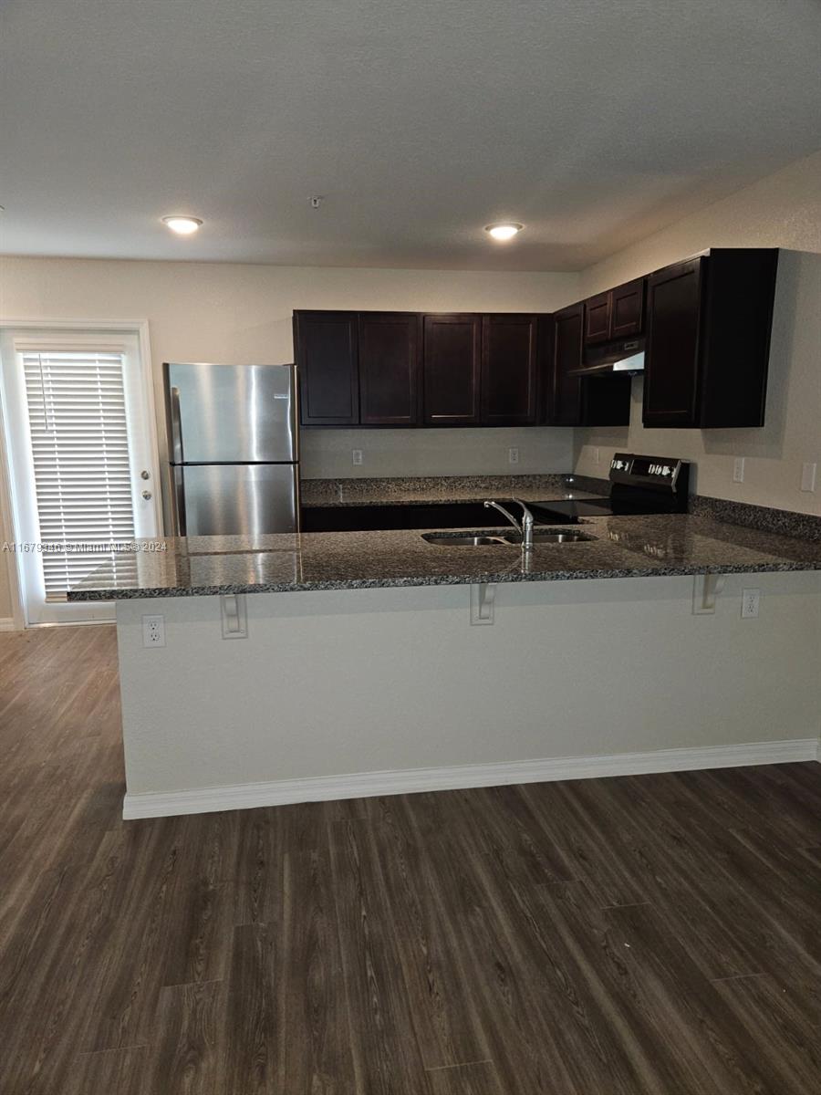 a view of kitchen with stainless steel appliances wooden floor