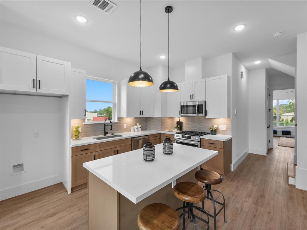 a kitchen with a table a stove a cabinets and wooden floor