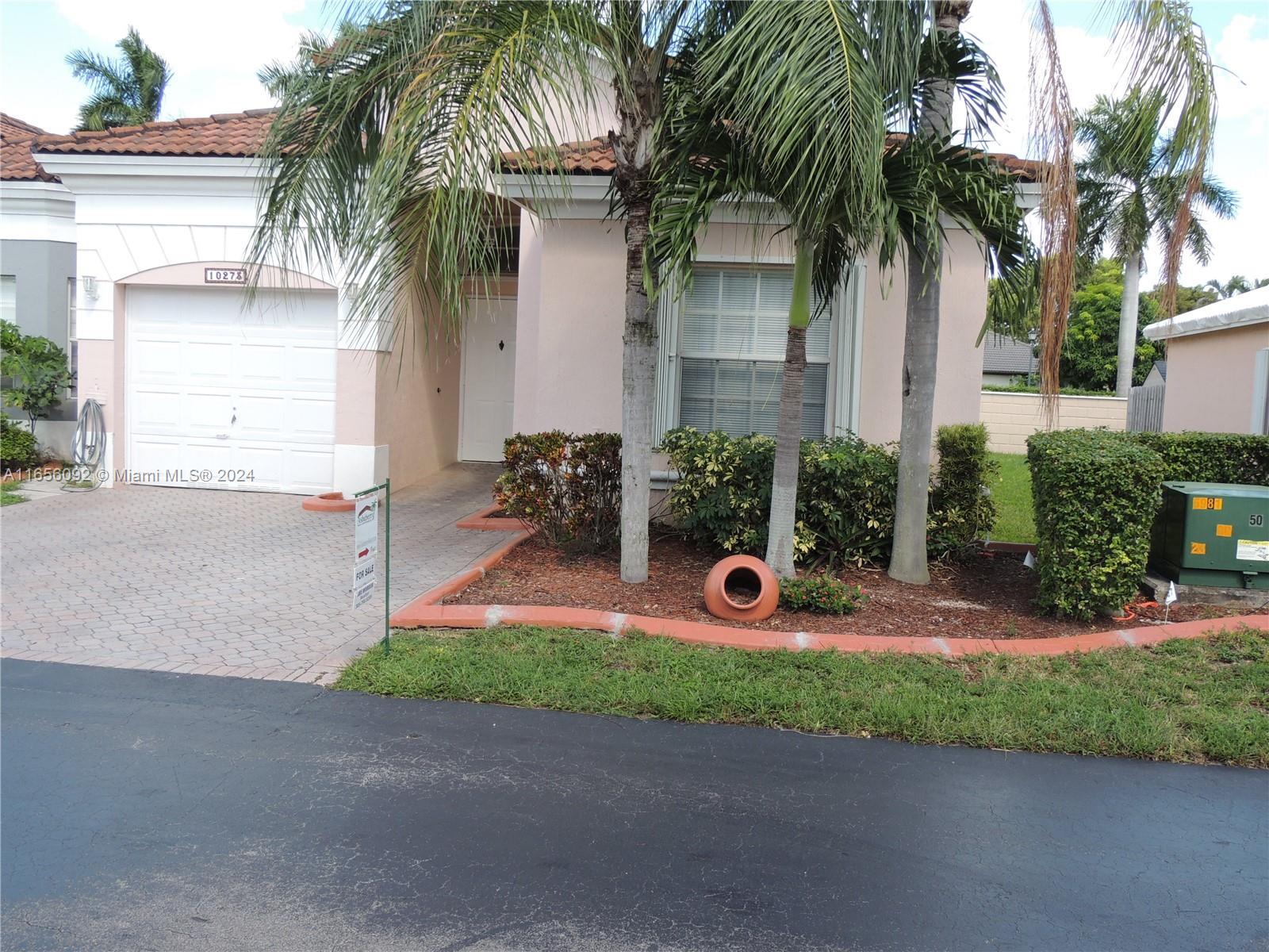 front view of house with potted plants and palm trees