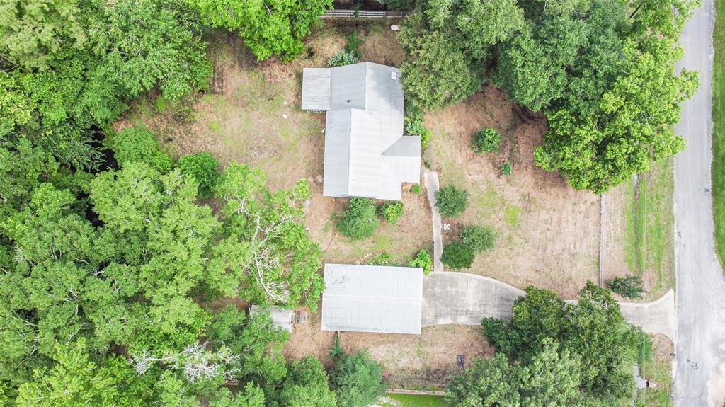 an aerial view of a house with outdoor space and trees all around