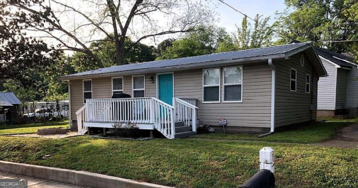 a view of a house with a yard chairs and a large tree