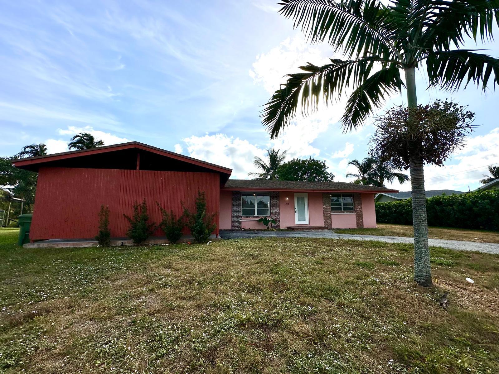 front view of house with a yard and palm trees