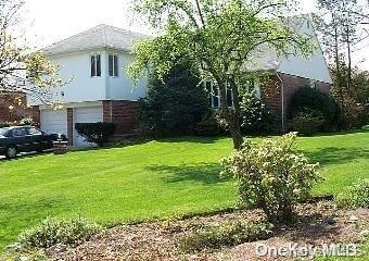 View of front facade featuring a front yard and a garage