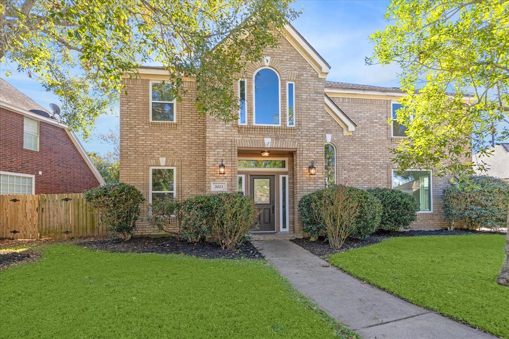 A beautiful two-story home with a charming brick exterior and well-manicured landscaping, showcasing its inviting curb appeal.