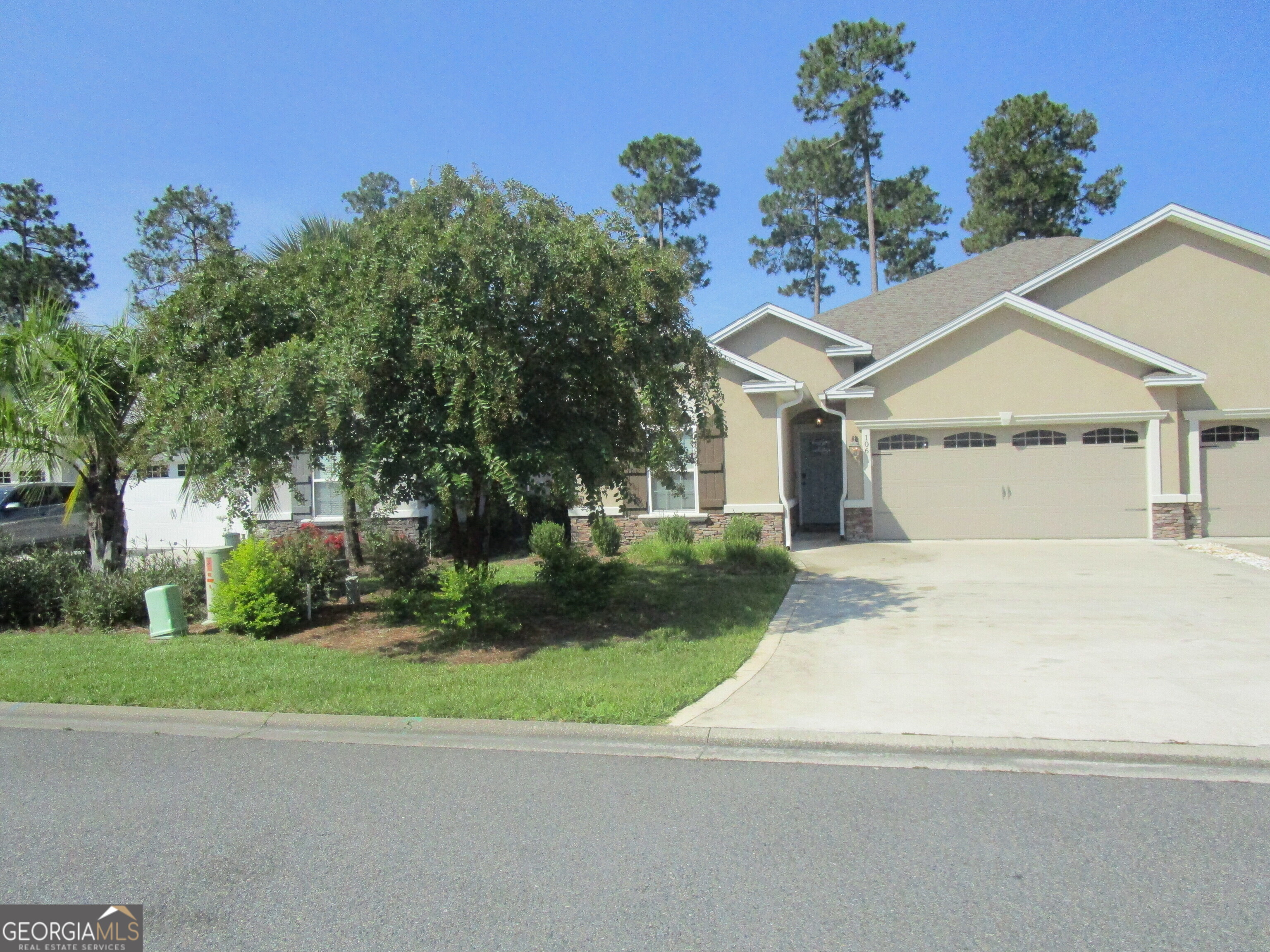 a view of a white house next to a yard and trees