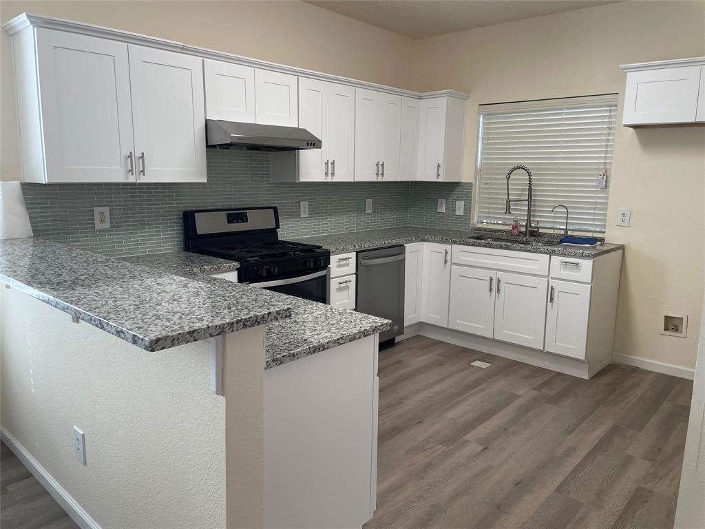 a kitchen with granite countertop a sink stove and cabinets