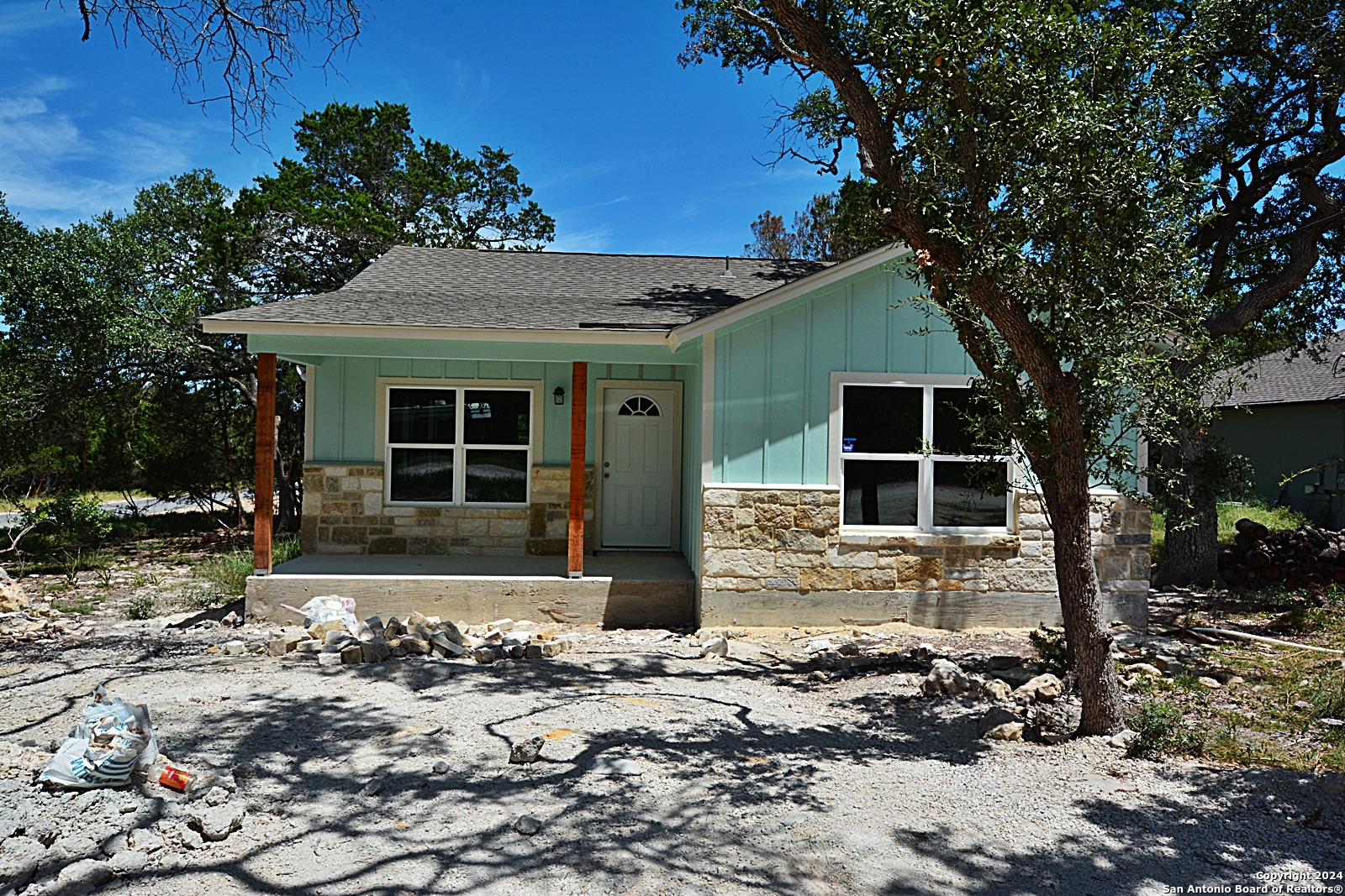 a front view of a house with a large tree