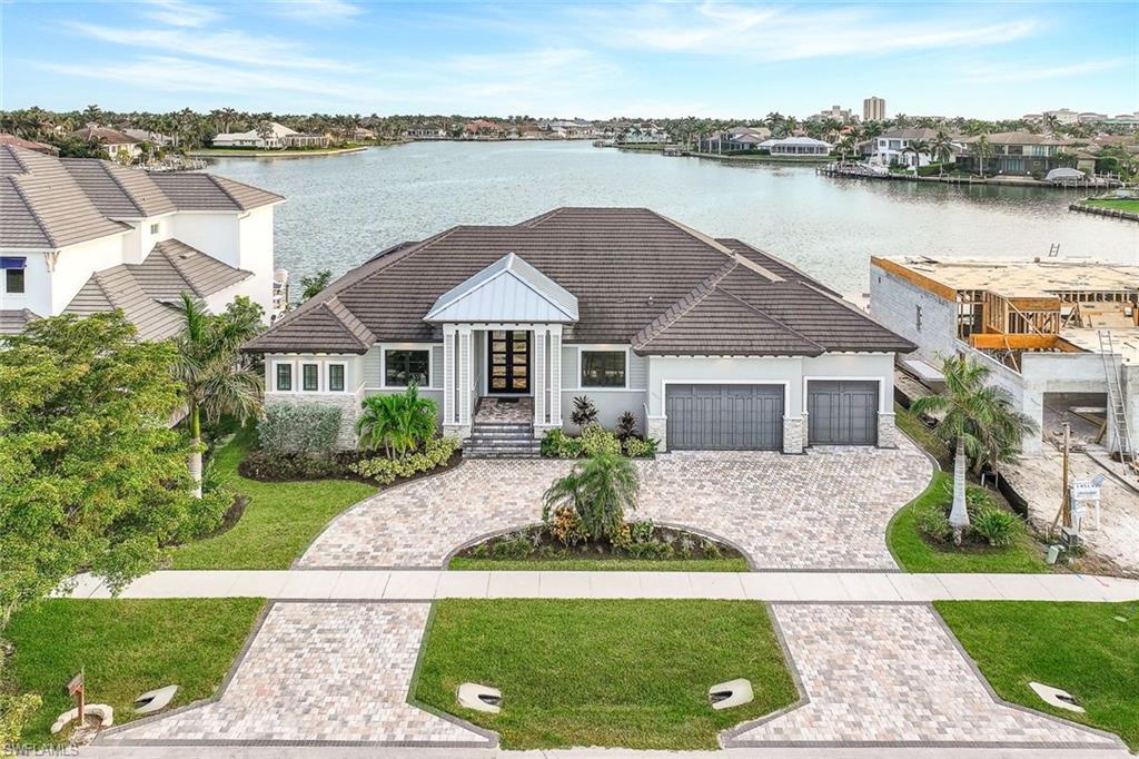 a front view of a house with a garden and lake view