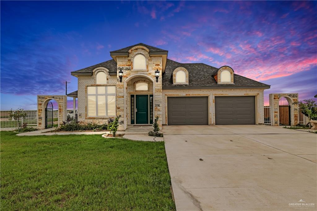 French country inspired facade with a lawn and a garage