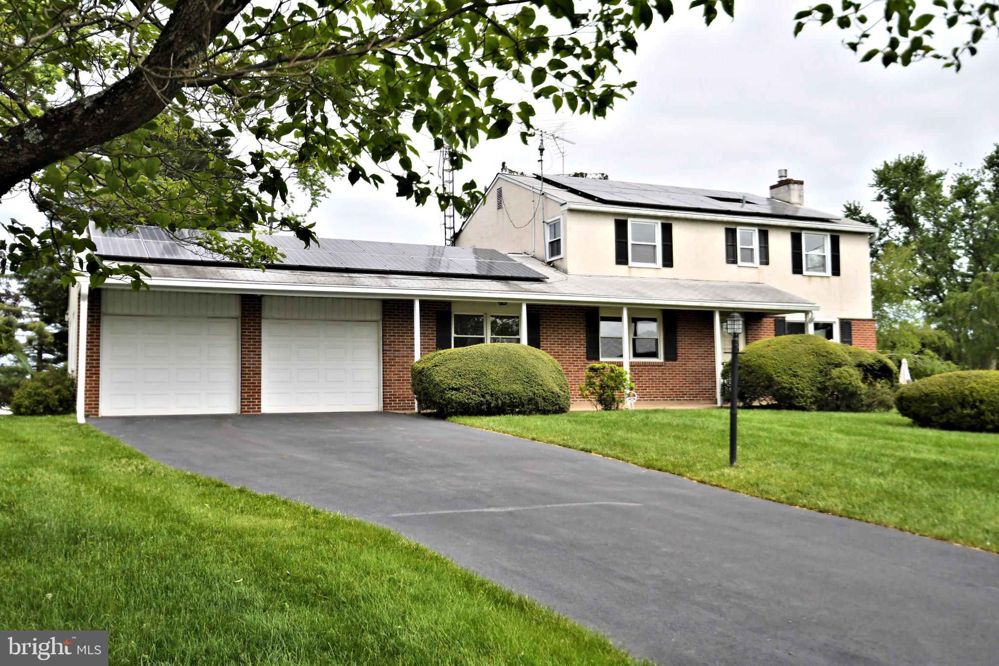 a front view of a house with a garden and trees