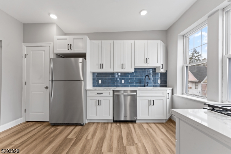 a kitchen with stainless steel appliances granite countertop a refrigerator sink and white cabinets