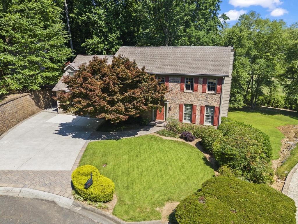 an aerial view of a house with swimming pool and large trees