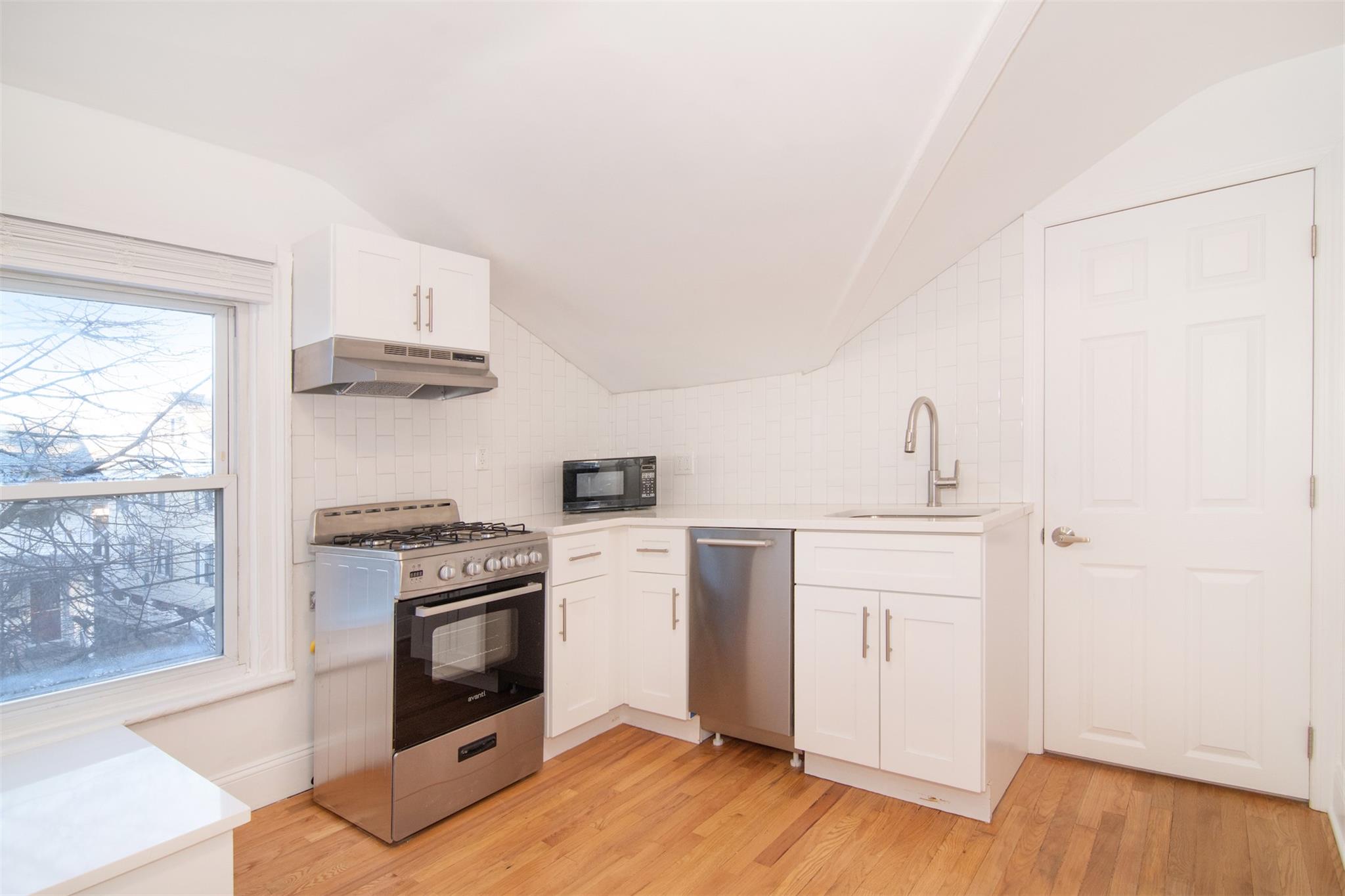 Kitchen featuring sink, white cabinets, stainless steel appliances, and light hardwood / wood-style floors