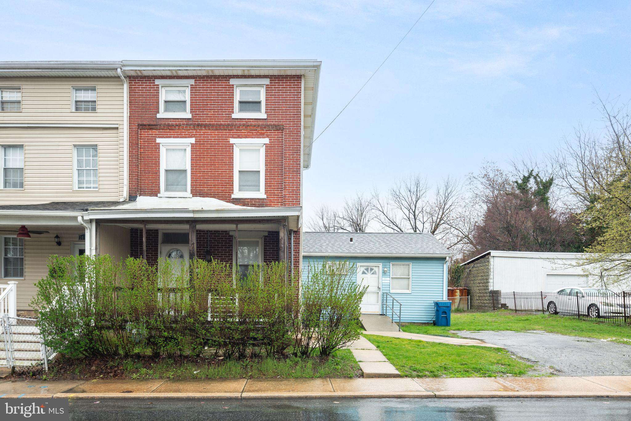 a view of a brick house with a yard plants and large tree