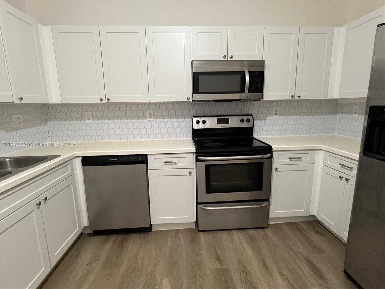 a kitchen with white cabinets and stainless steel appliances