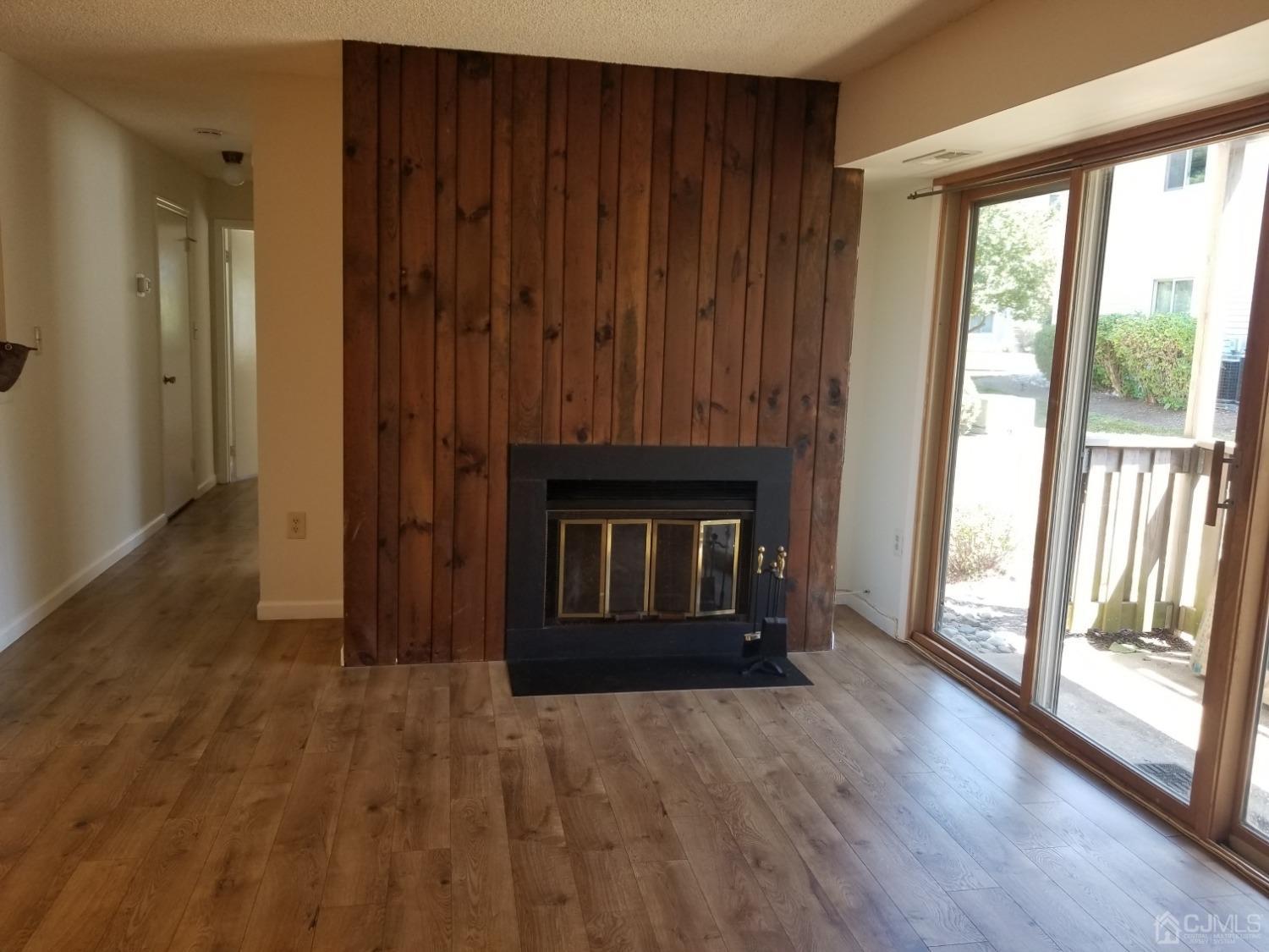 an empty room with wooden floor fireplace and windows