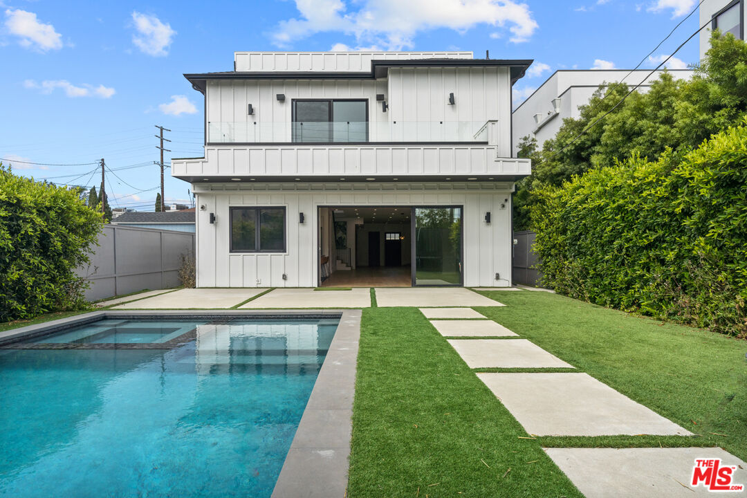 a view of a white house with a swimming pool and a yard with plants