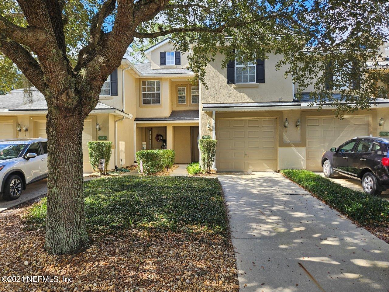 a front view of a house with a garden and tree