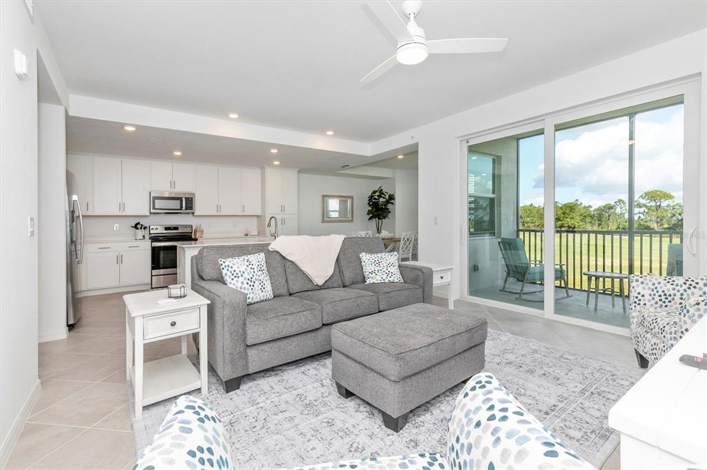 a living room with furniture and a large window with kitchen view