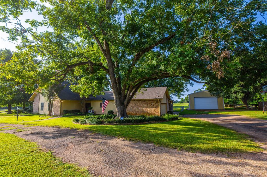 a view of a house with a big yard and large trees