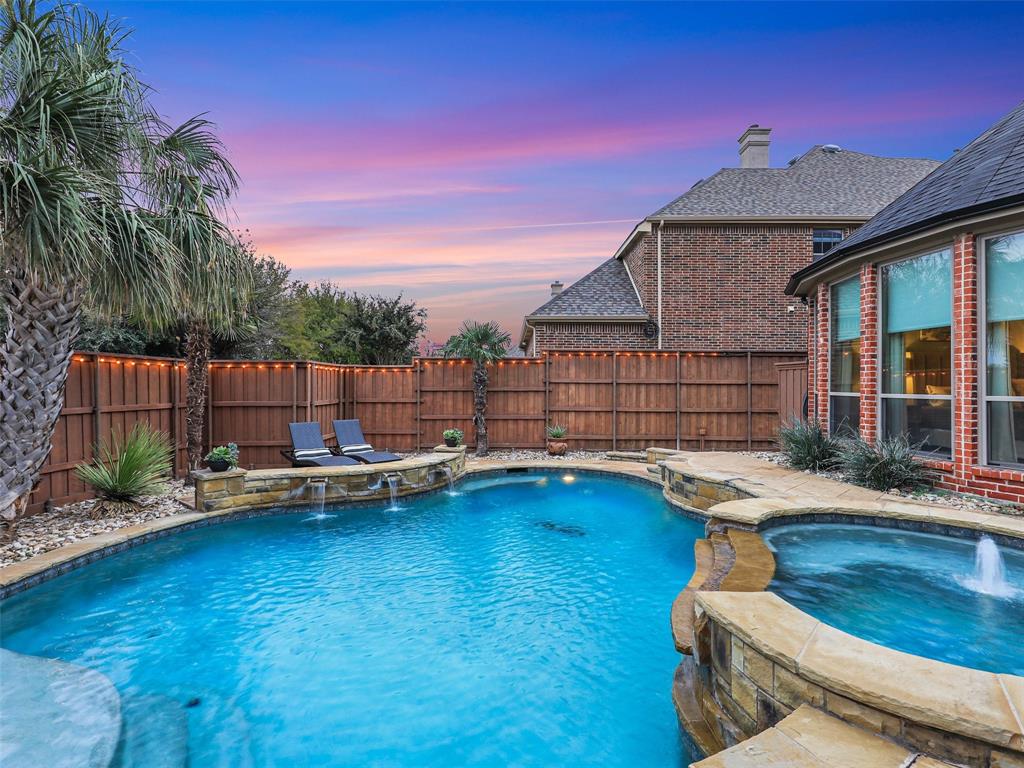 Stunning Twin Creeks Highland home with sparkling Lagoon-style Pool featuring water features, 8 ft. privacy fence, tanning ledge, upstairs balcony, landscaping, in ground hot tub with water feature plus grassy sideyard.