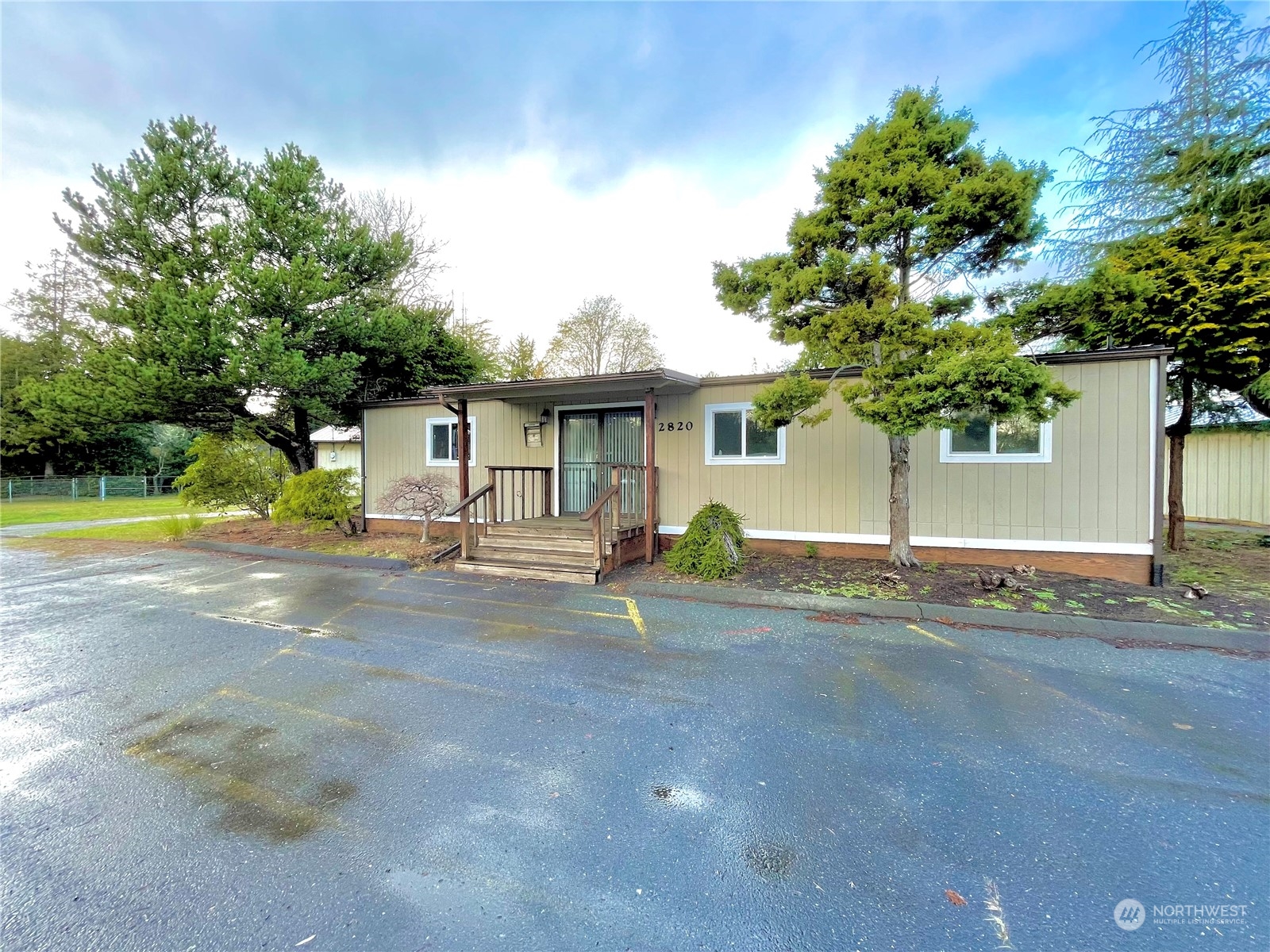 a front view of a house with garden and a tree