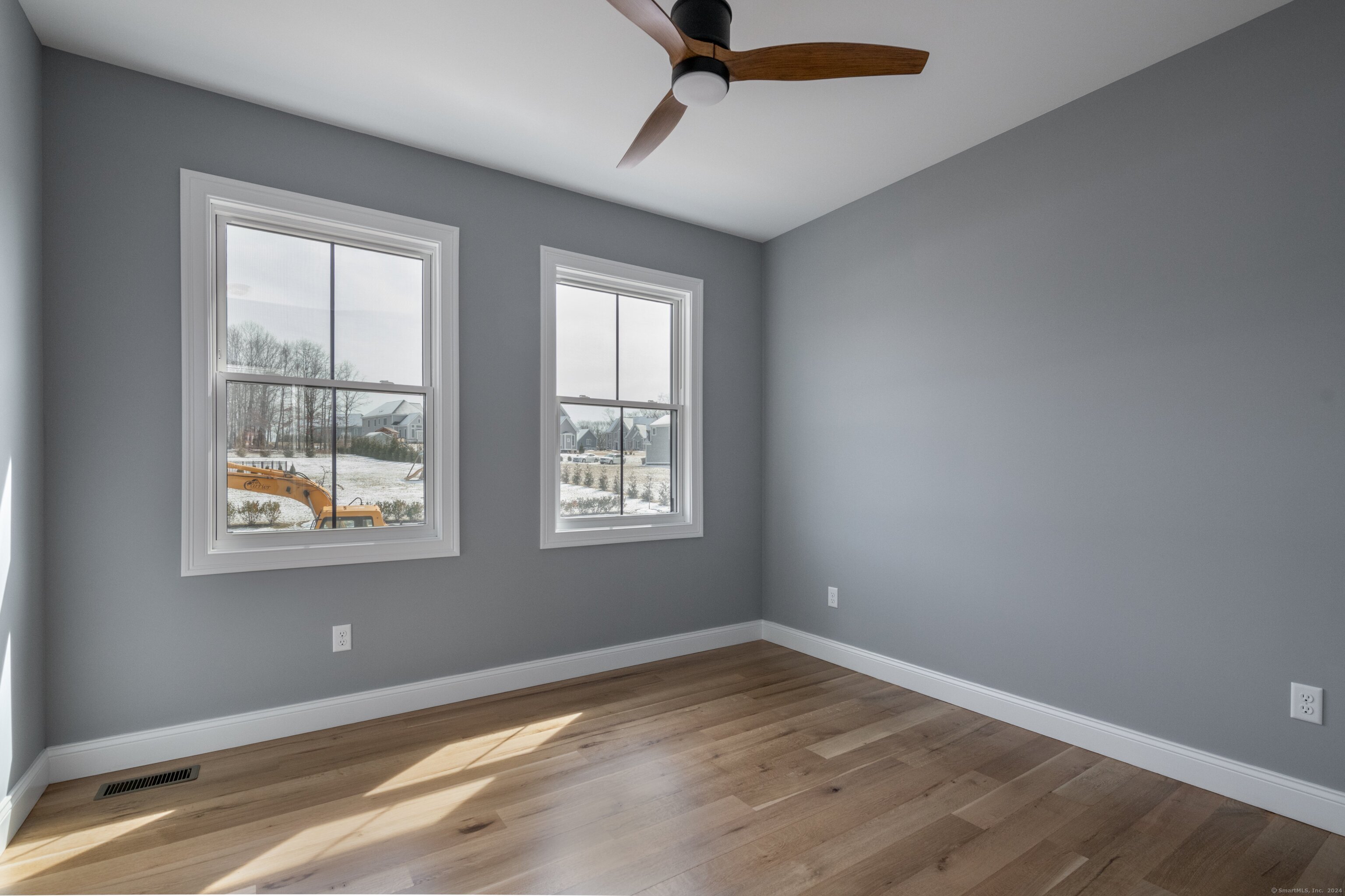 a view of empty room with wooden floor and fan