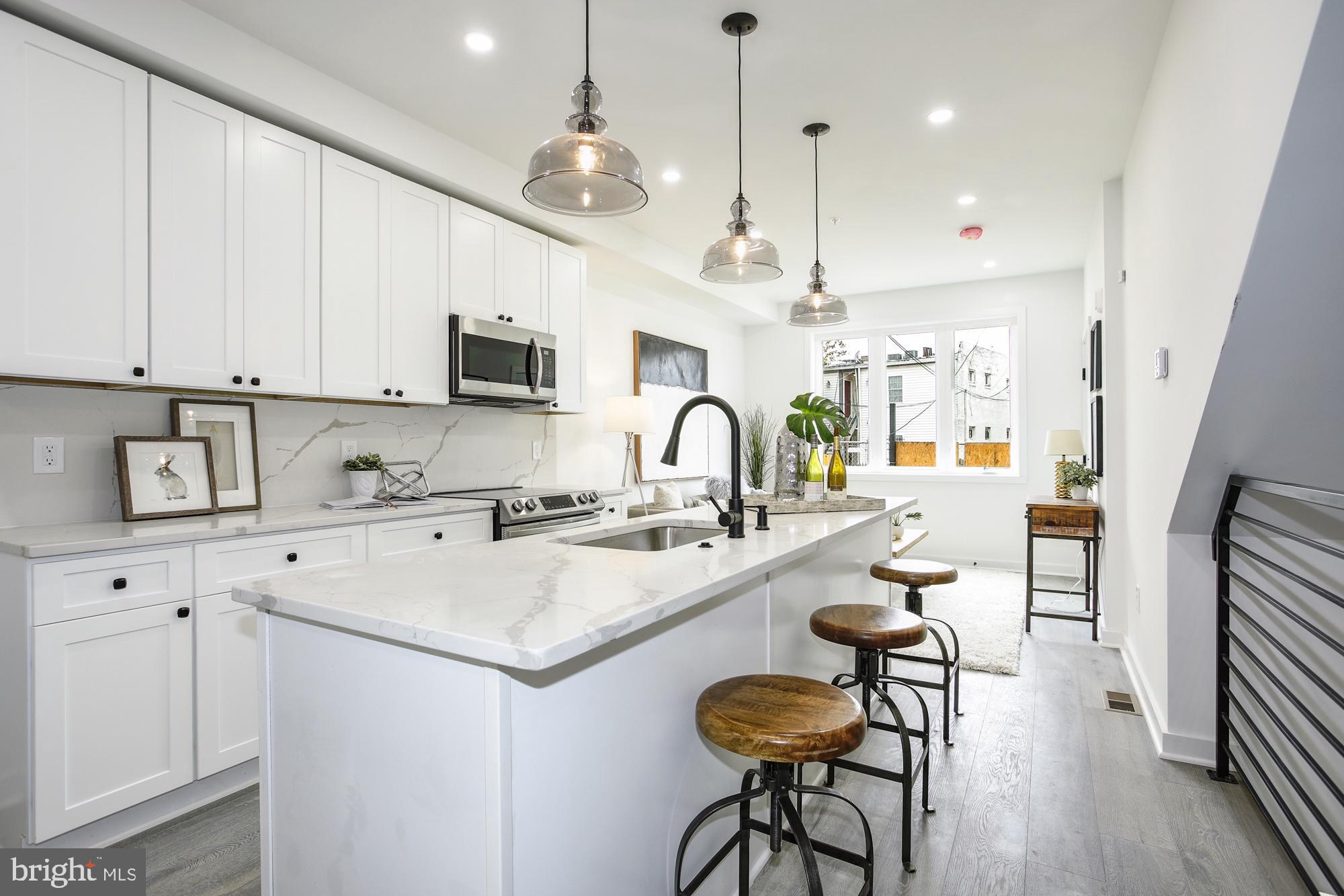 a kitchen with sink stove and white cabinets with wooden floor