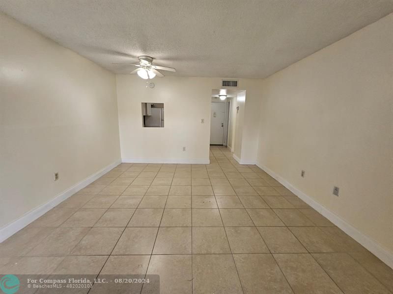 a view of an empty room with a ceiling fan and window