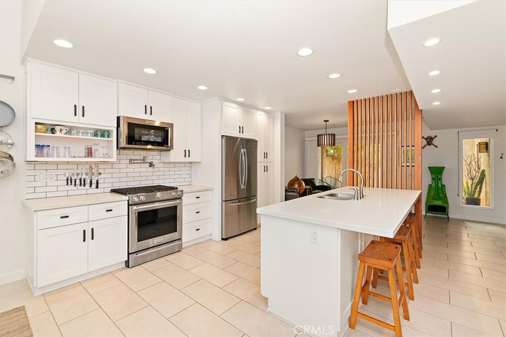 a kitchen with stainless steel appliances kitchen island granite countertop a stove top oven a sink dishwasher and a refrigerator with wooden floor