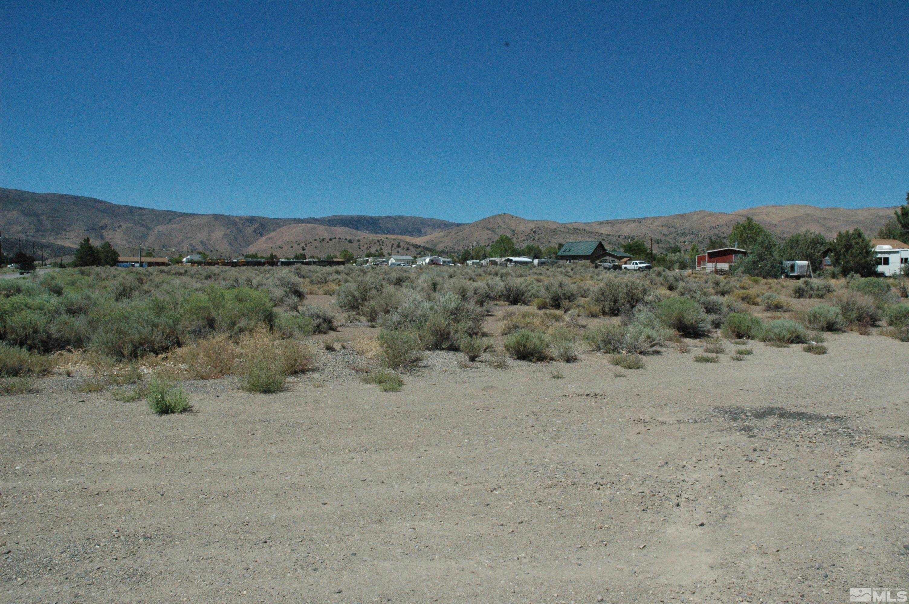 a view of a dry field with mountains in the background