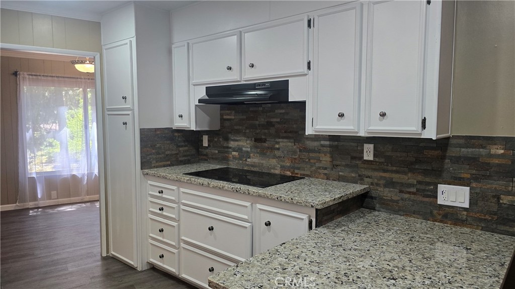 a kitchen with granite countertop white cabinets and white appliances