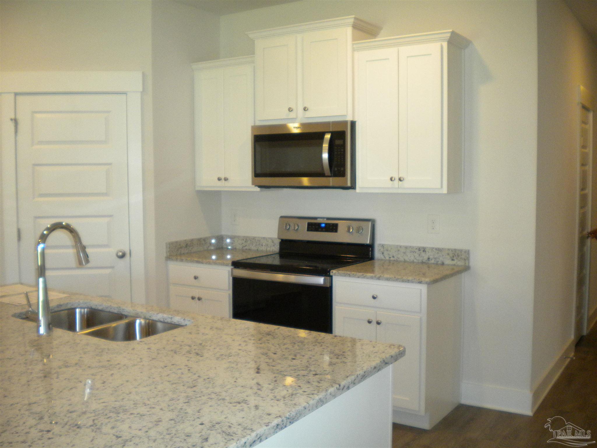 a kitchen with stainless steel appliances granite countertop a stove a sink and a microwave