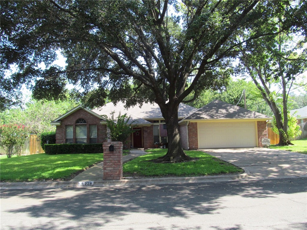 a front view of a house with a garden and trees