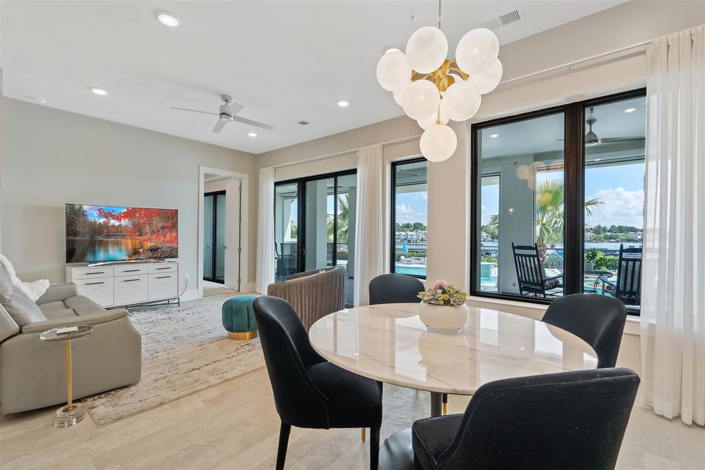 a view of a dining room with furniture a chandelier and large windows