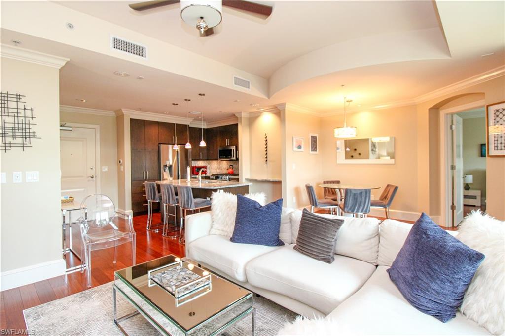 Living room with dark wood-type flooring, ceiling fan, and crown molding