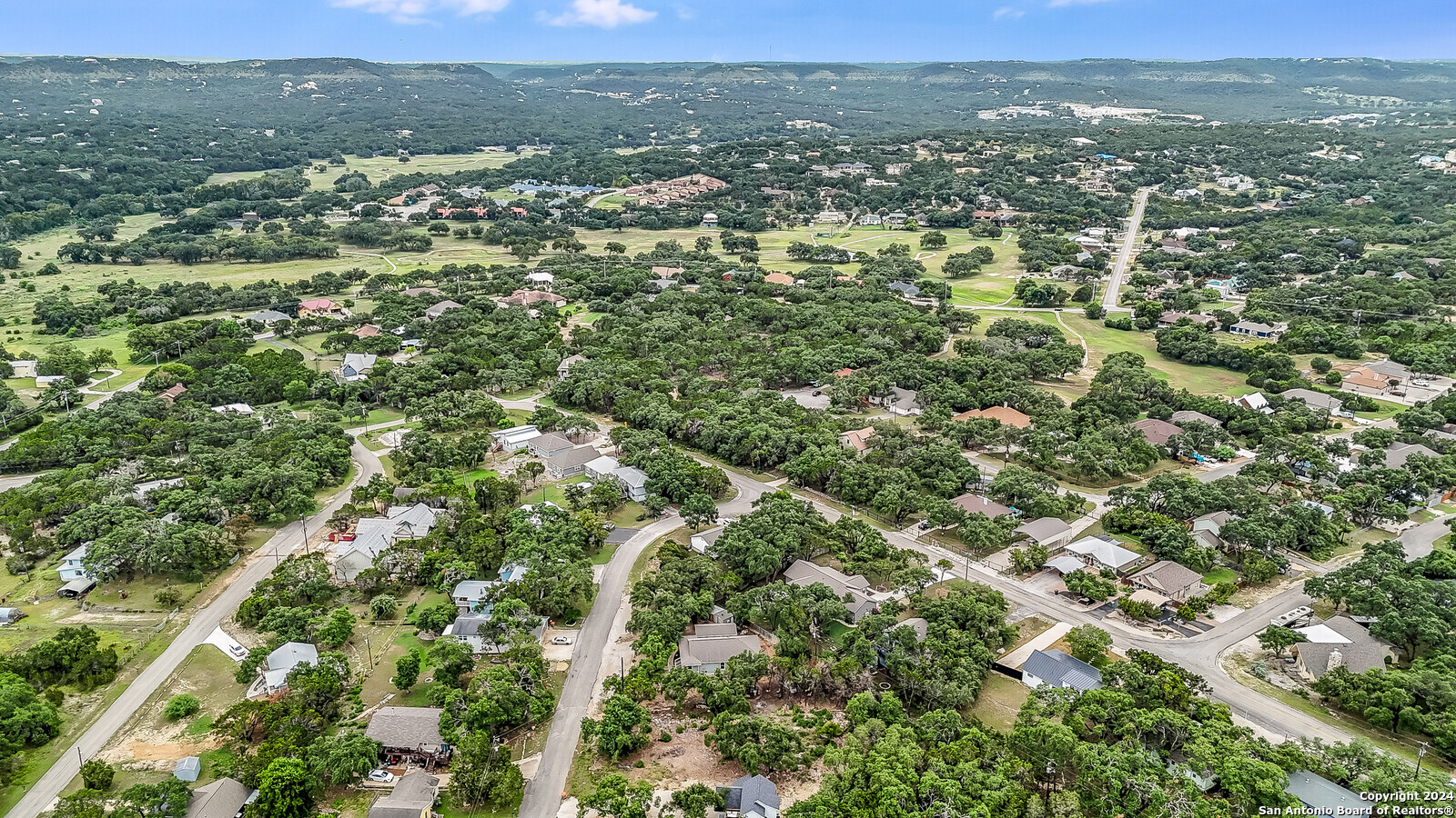 an aerial view of residential houses with outdoor space and trees