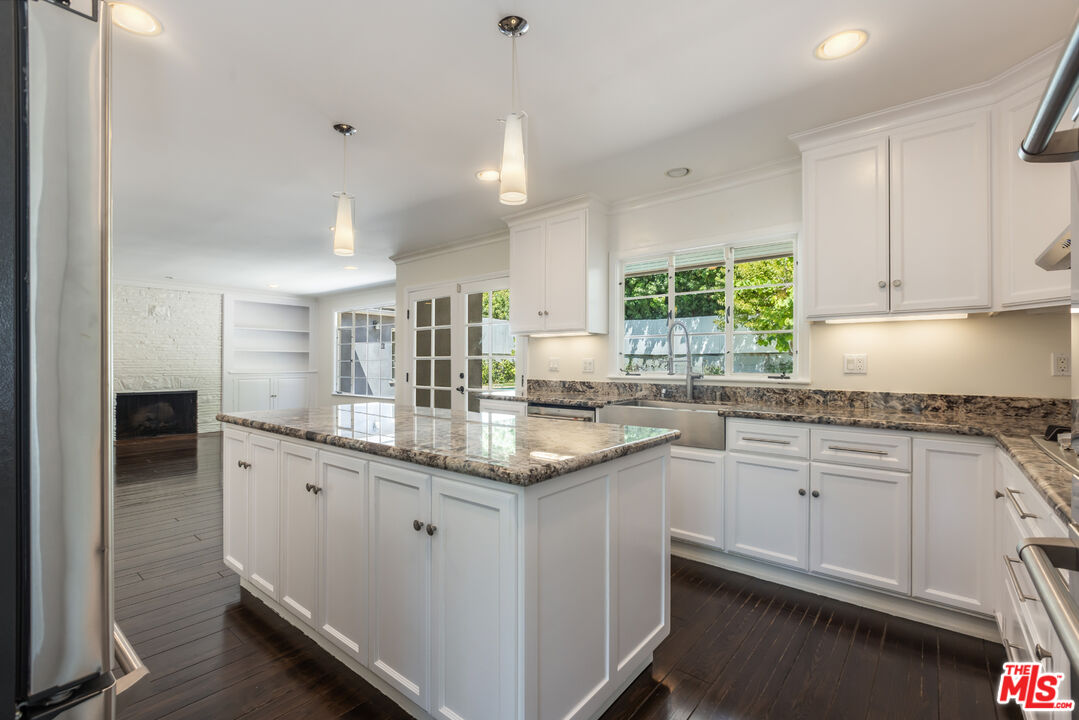 a kitchen with granite countertop kitchen island white cabinets and appliances