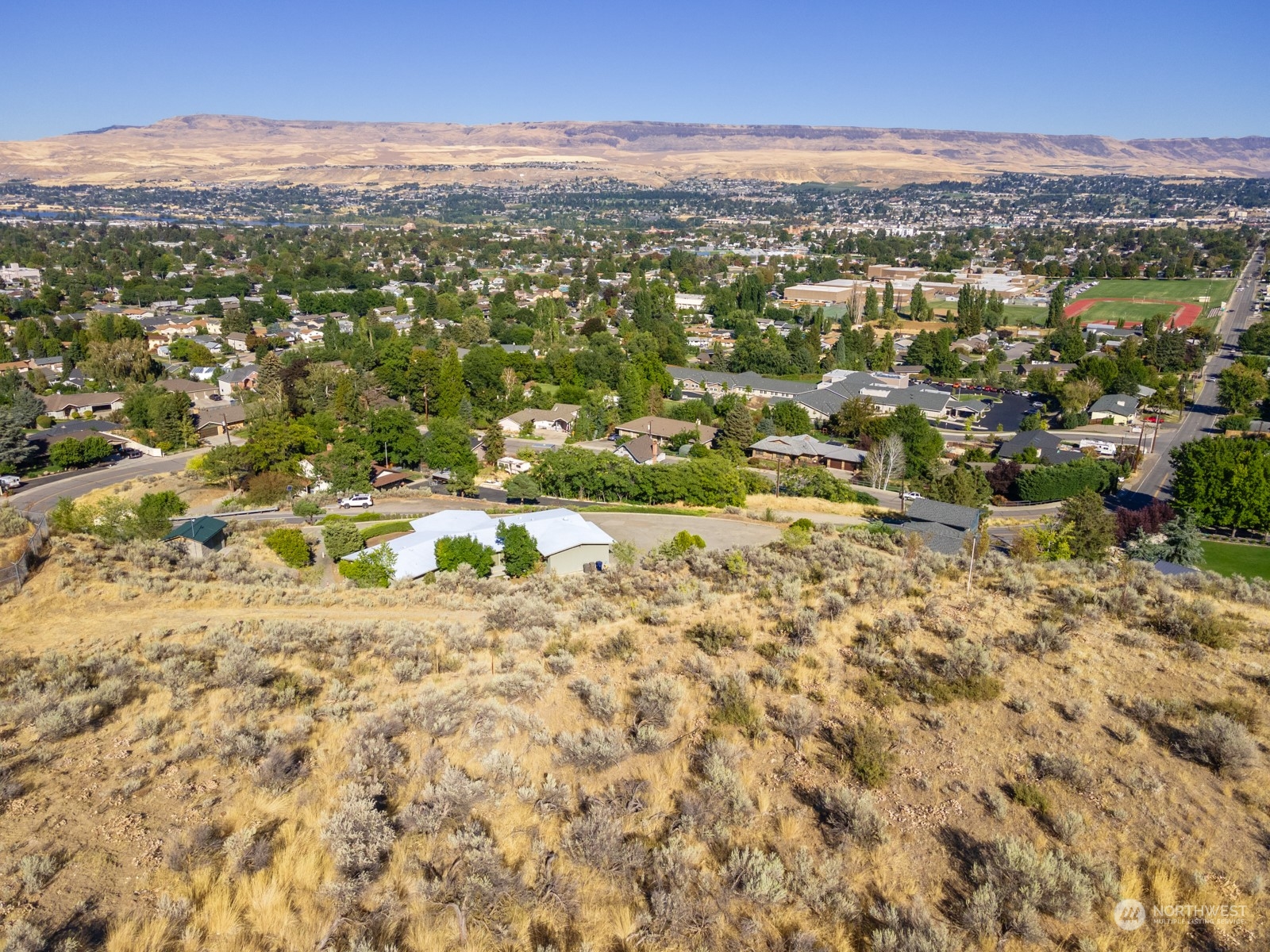 an aerial view of residential houses with outdoor space and trees