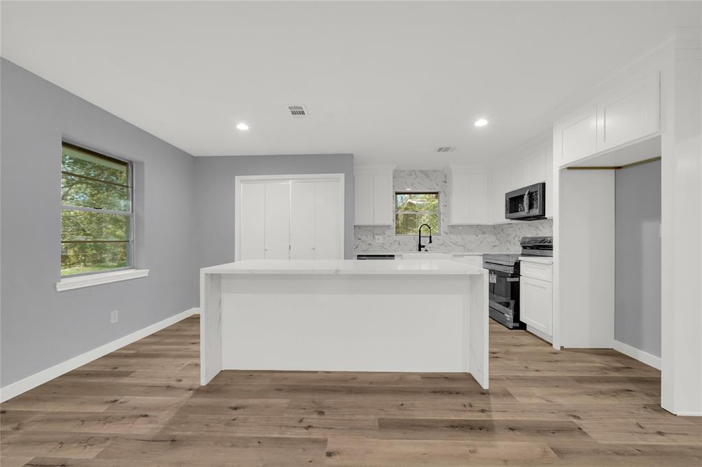 a view of kitchen with stainless steel appliances granite countertop cabinets and wooden floor