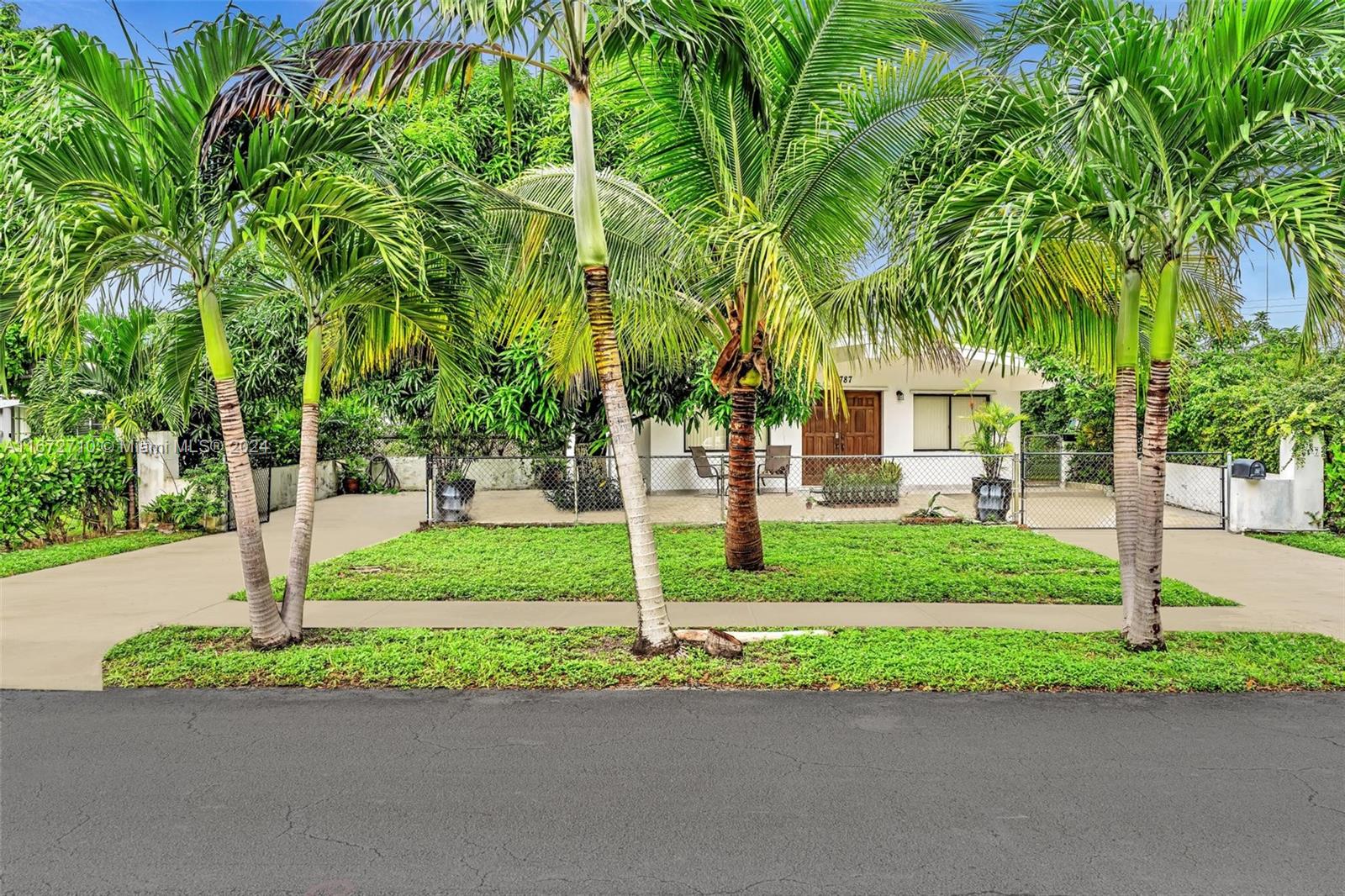 a view of a house with a small yard and palm trees